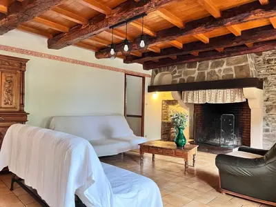 a living room with a stone fireplace and a couch at Grand gîte proche des lacs in Prémian