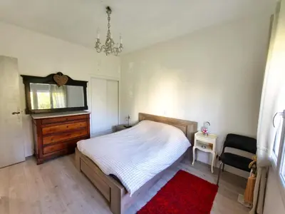 a bedroom with a bed and a dresser and a red rug at La 1848 Narbonnaise in Narbonne