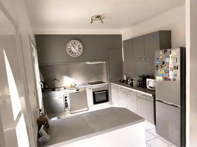a kitchen with a refrigerator and a clock on the wall at La 1848 Narbonnaise in Narbonne
