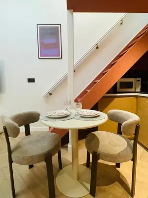 a table and chairs in a room with a staircase at Maison Franz - 800m des Grands Buffets - Garage in Narbonne