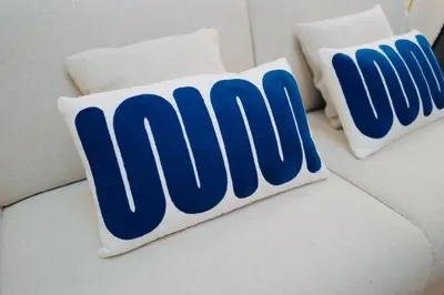 two blue and white pillows on a white couch at Maison Franz - 800m des Grands Buffets - Garage in Narbonne