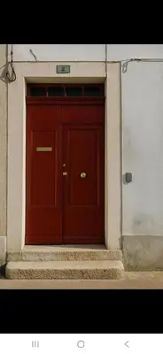 a red door in the side of a building at Appartement avec deux chambres et salon de massage in Lavelanet