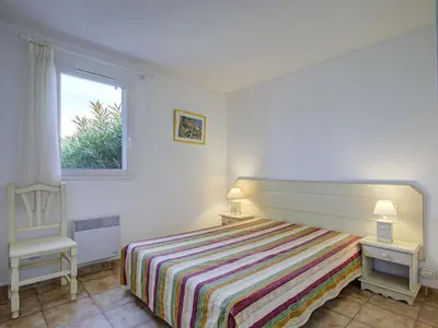 a bedroom with a bed and a chair and a window at P Minervois L N02 Villa 3P6 in Homps