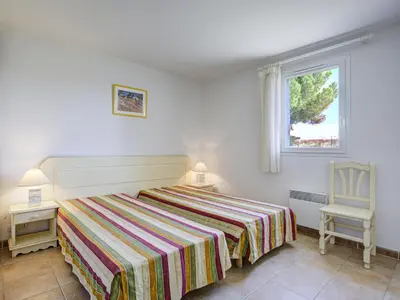 a bedroom with a bed and a chair and a window at P Minervois S N06 Villa 4P8 in Homps