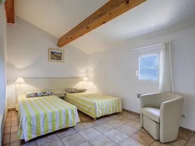 a bedroom with two beds and a chair at P Minervois J N03 Villa 3P6 in Homps