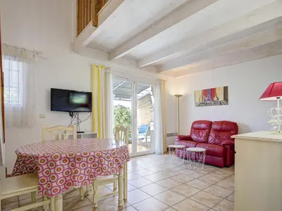 a living room with a table and a red chair at P Minervois J N03 Villa 3P6 in Homps