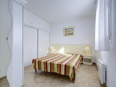 a white bedroom with a bed and a table at P Minervois P N05 Villa 2P4 in Homps