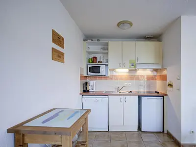a small kitchen with white cabinets and a wooden table at P Minervois P N05 Villa 2P4 in Homps