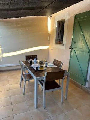 a table and chairs in a room with a green door at P Minervois G N02 Villa 3P4 in Homps