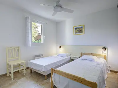 a bedroom with two beds and a chair and a window at P Minervois U N04 VILLA 3P6 in Homps