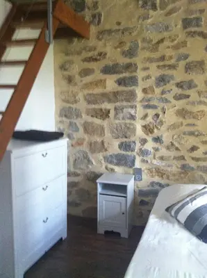 a bedroom with a bed and a stone wall at Écurie De Cucugnan in Cucugnan