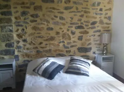 a bedroom with a bed with two pillows and a stone wall at Écurie De Cucugnan in Cucugnan