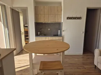 a kitchen with a wooden table in a room at Les pieds dans l'eau Studio Cabine terrasse, refait à neuf 5 minutes plage à pied climatisé in Gruissan