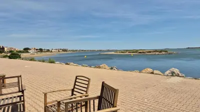 two chairs sitting on a beach next to a body of water at Les pieds dans l'eau Studio Cabine terrasse, refait à neuf 5 minutes plage à pied climatisé in Gruissan