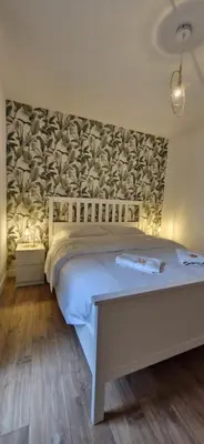 a bedroom with a white bed with a wall at La Romana in Narbonne