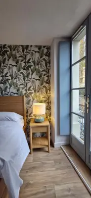 a bedroom with a bed and a table with a lamp at La Romana in Narbonne