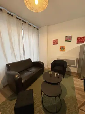 a living room with a leather couch and a table at La coloc' l 3 Chambres avec salle de bain & TV in Castres