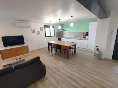 a living room with a dining room table and a kitchen at Appart spacieux, cosy clim aux portes de Carcassonne in Pennautier