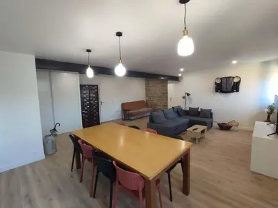 a living room with a wooden table and a couch at Appart spacieux, cosy clim aux portes de Carcassonne in Pennautier