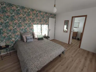 a bedroom with a bed and a flowered wall at Appart spacieux, cosy clim aux portes de Carcassonne in Pennautier