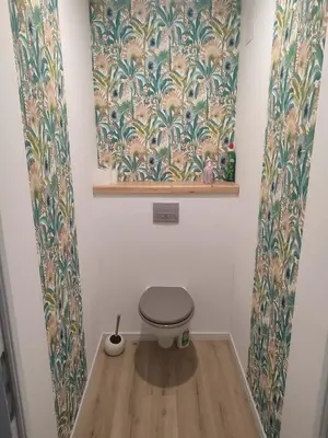 a bathroom with a toilet in a room with wallpaper at Appart spacieux, cosy clim aux portes de Carcassonne in Pennautier