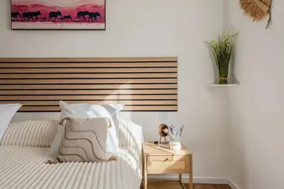 a bedroom with a white bed with a wooden headboard at La douce echappee in Trèbes