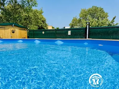 a swimming pool with blue water in front of a fence at La douce echappee in Trèbes