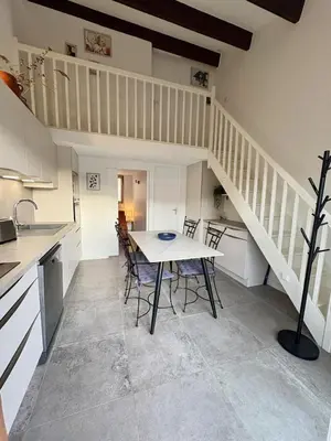 a kitchen with a table and chairs and a staircase at Pavillon moderne & spacieux - accès direct plage in Gruissan