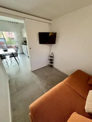 a living room with a couch and a television on the wall at Pavillon moderne & spacieux - accès direct plage in Gruissan