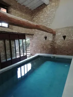 a swimming pool in a building with a stone wall at La maison de la fontaine in Villeneuve-Minervois