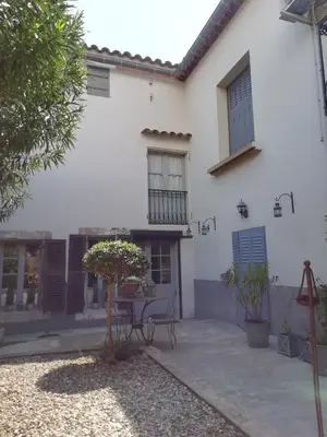 a white house with a table in the courtyard at La maison de la fontaine in Villeneuve-Minervois