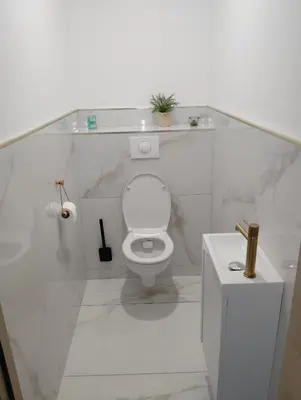 a white bathroom with a toilet and a sink at Maison de ville - Les Grands Buffets in Narbonne
