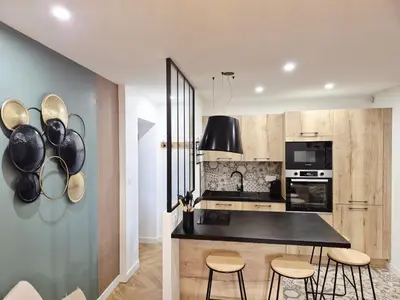 a kitchen with a black counter top and some stools at Appartement l'Atelier Cosy in Narbonne