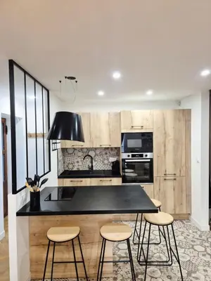 a kitchen with a black counter top and some stools at Appartement l'Atelier Cosy in Narbonne
