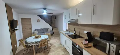 a kitchen with a table and a living room at Le Donjon du Chateau in Tournissan