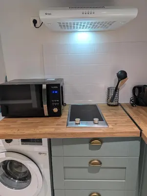 a kitchen with a microwave and a washing machine at Le Cocon de Pezens - Studio au centre du village in Pezens