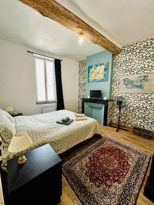 a bedroom with a bed and a table with a rug at Maison de village avec piscine 8 personnes in Ouveillan