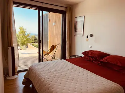 a bedroom with a bed and a sliding glass door at Plein Soleil in Félines-Minervois