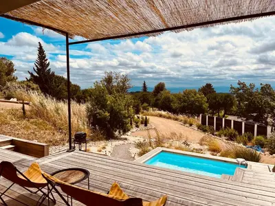 a deck with two chairs and a swimming pool at Plein Soleil in Félines-Minervois
