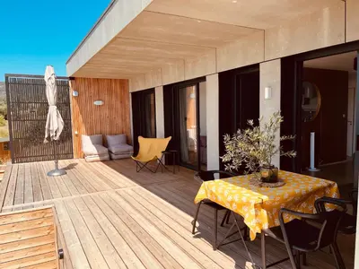 a wooden deck with a table and a couch at Plein Soleil in Félines-Minervois