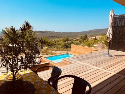 a wooden deck with a table and chairs and a pool at Plein Soleil in Félines-Minervois