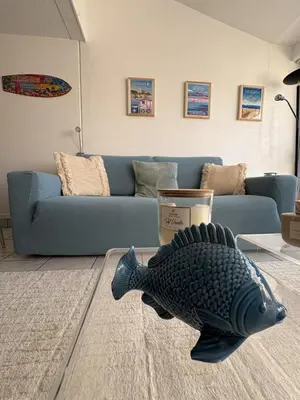 a living room with a blue couch and a fish statue at Marina au bord de l'eau accès direct port in Gruissan