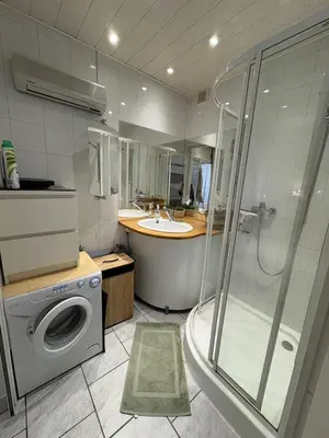 a bathroom with a shower and a sink and a washing machine at Marina au bord de l'eau accès direct port in Gruissan