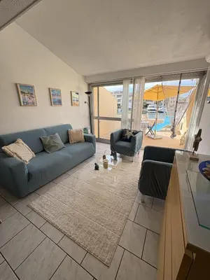 a living room with a blue couch and a table at Marina au bord de l'eau accès direct port in Gruissan
