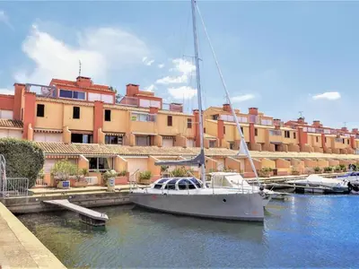 a sail boat docked in a marina in front of a building at Marina au bord de l'eau accès direct port in Gruissan