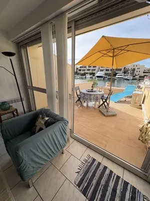 a living room with a couch and a patio with an umbrella at Marina au bord de l'eau accès direct port in Gruissan