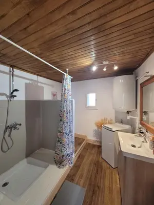 a large kitchen with white cabinets and a wooden floor at Havre de paix entre montagne et forêt
