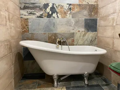 a white bath tub in a bathroom with tiles at Studio climatisé avec terrasse in Narbonne