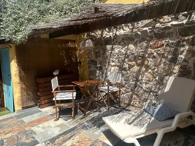 a patio with chairs and a table and a stone wall at Studio climatisé avec terrasse in Narbonne
