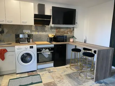 a kitchen with a washing machine and a counter with stools at Studio climatisé avec terrasse in Narbonne